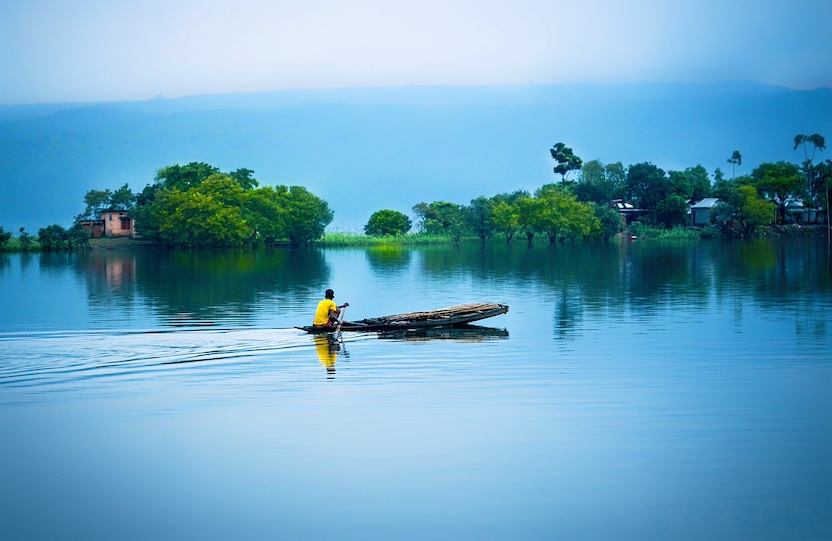 tranquil lake with boatman in bangladesh.