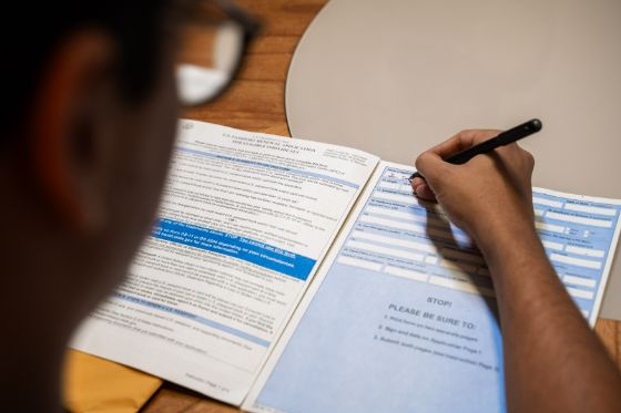 a young man filling out passport renewal form DS-82 with a pen