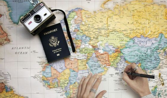 woman's hands drawing on a map with a passport and camera resting on it
