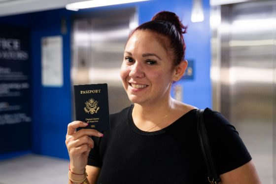 A woman smiles as she holds her newly-issued, passport following a name change at the Miami Regional Passport Agency